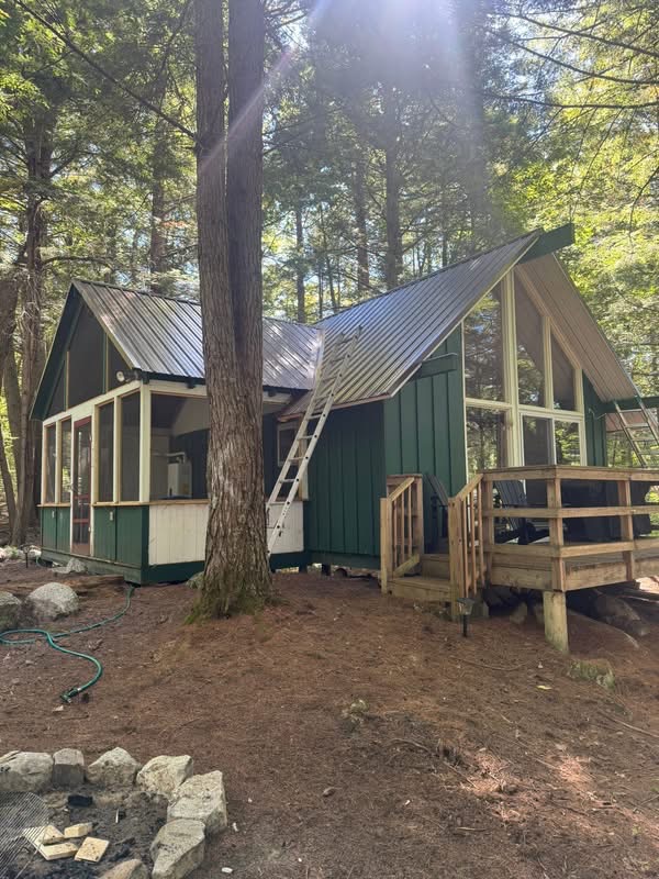 A-frame cabin with new black metal roof in the woods