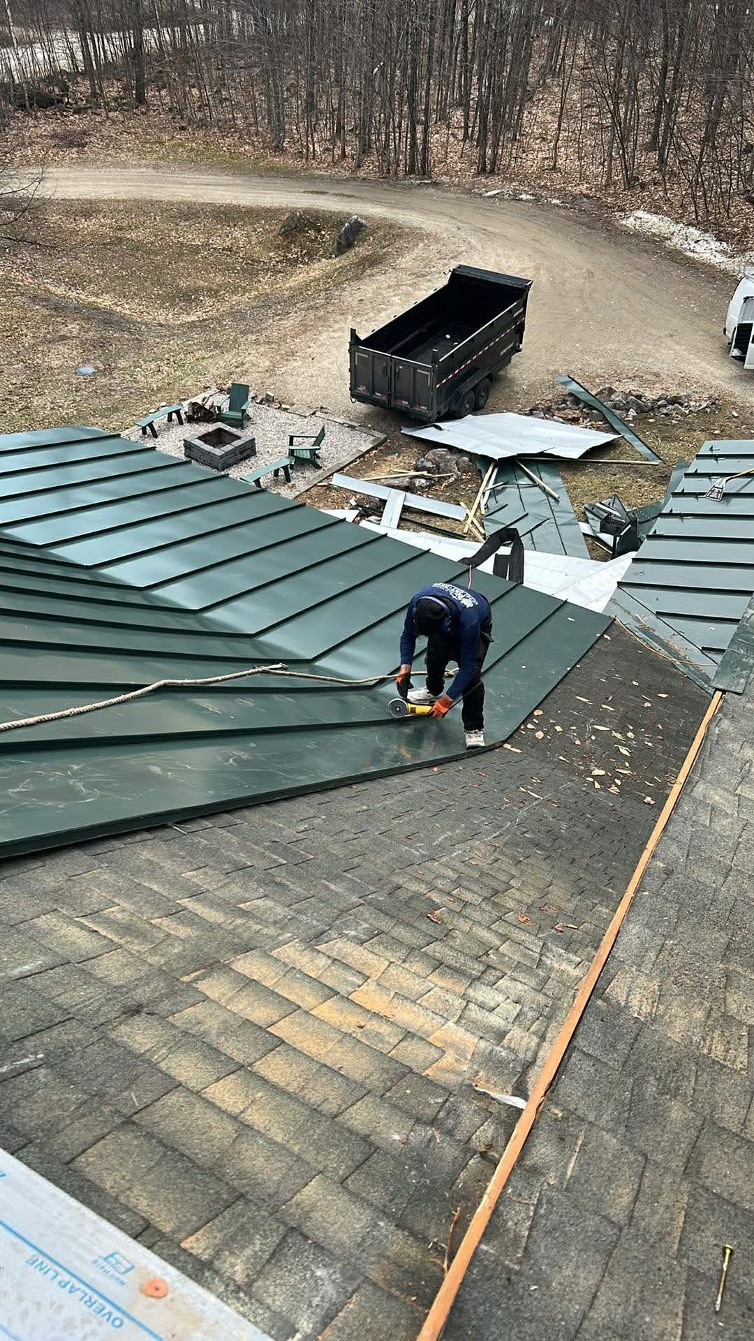 Green standing seam metal roof installation over existing shingles